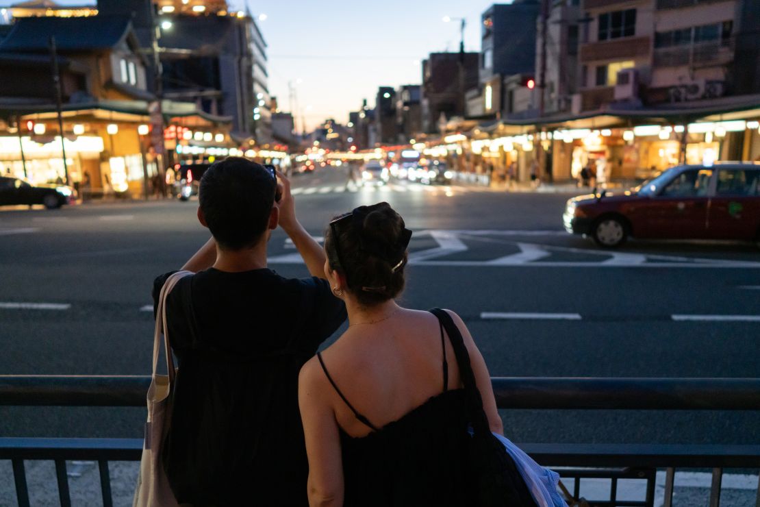 A tourist takes a photograph outside Yasaka Shrine at dusk on August 8, 2024 in Kyoto, Japan.