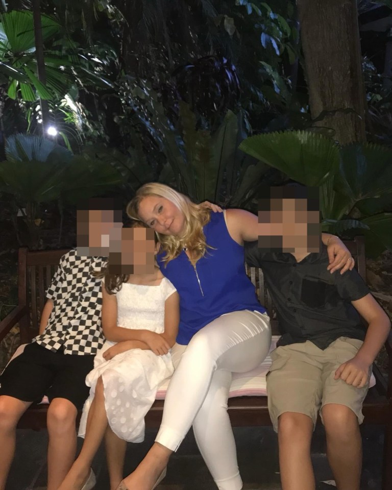 Woman sitting on a bench with two children.