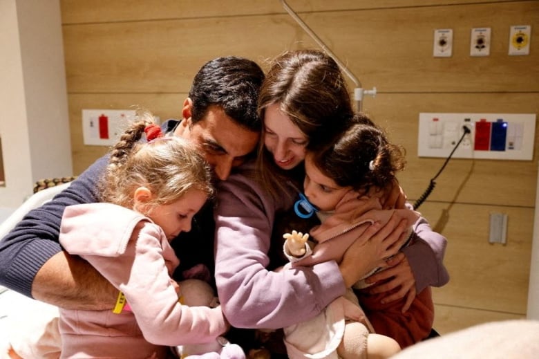 Two adults and two children embrace.