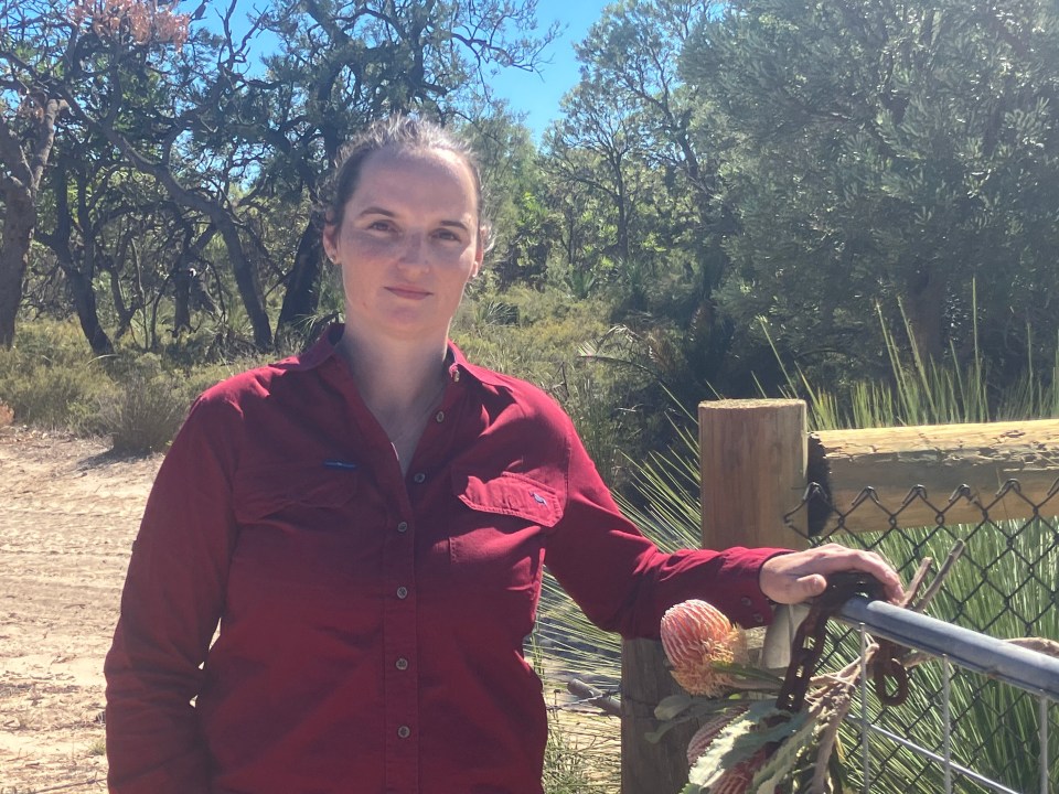 Karrie Louden standing by a gate in a natural setting.