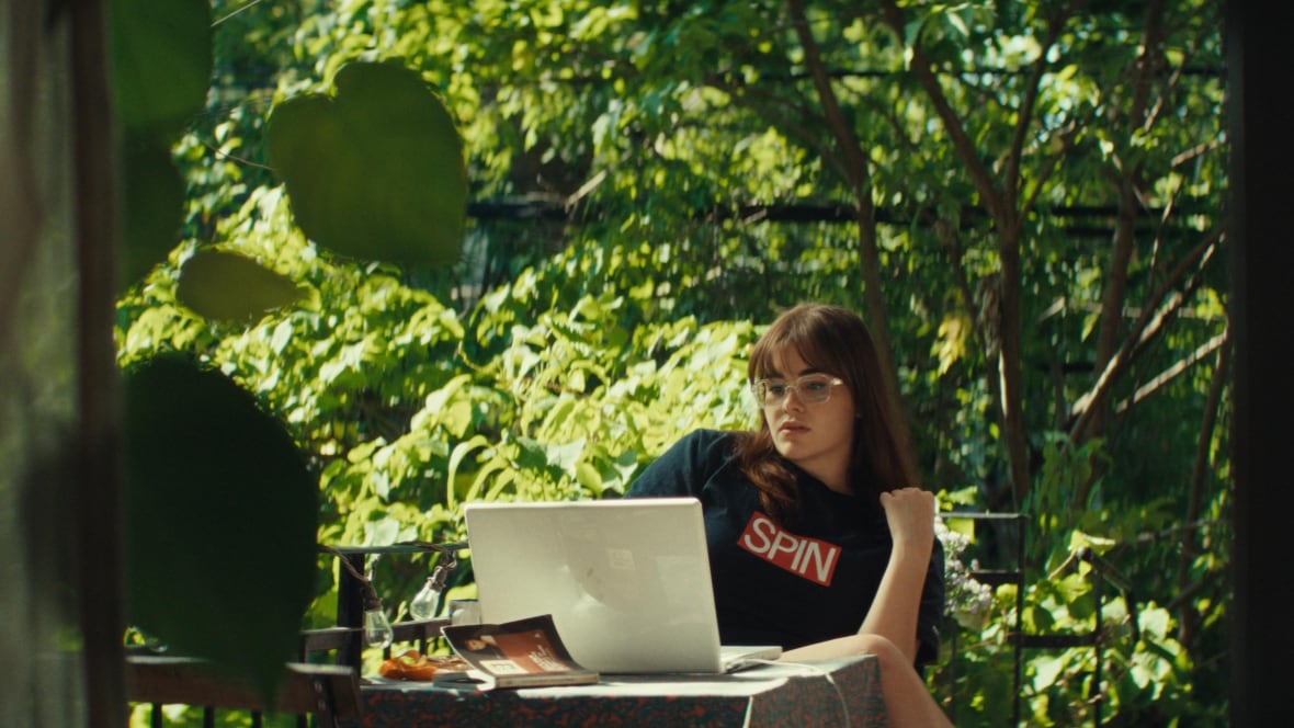 A woman wearing a 'Spin' t-shirt sits in front of a laptop.