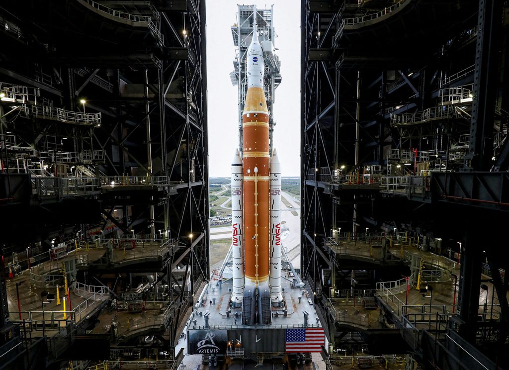NASA's next-generation moon rocket, the Space Launch System (SLS) rocket with the Orion crew capsule, rolls from the Vehicle Assembly Building