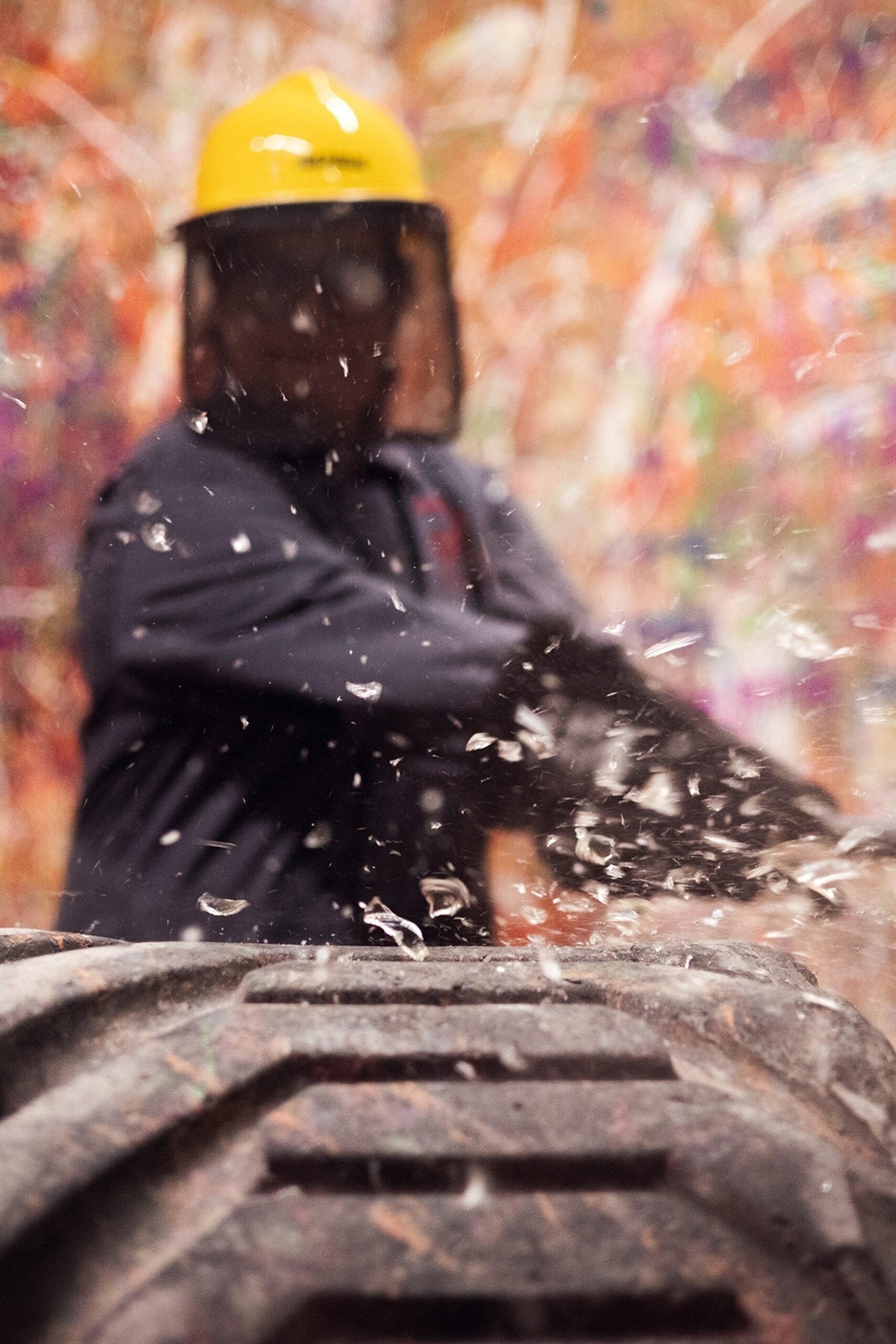 A dynamic shot of a person with protective visor and boiler suit smashing a glass with a bat on a tyre.