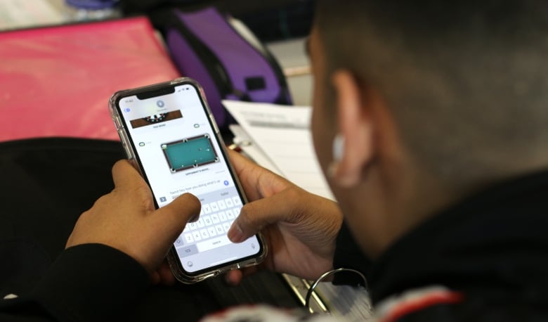 A high school student uses a cellphone in class.