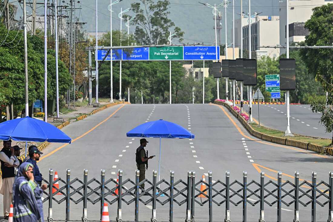 Security personnel stand guard at a closed road leading to the Serena Hotel in the Red Zone area of Islamabad on April 23, 2026.