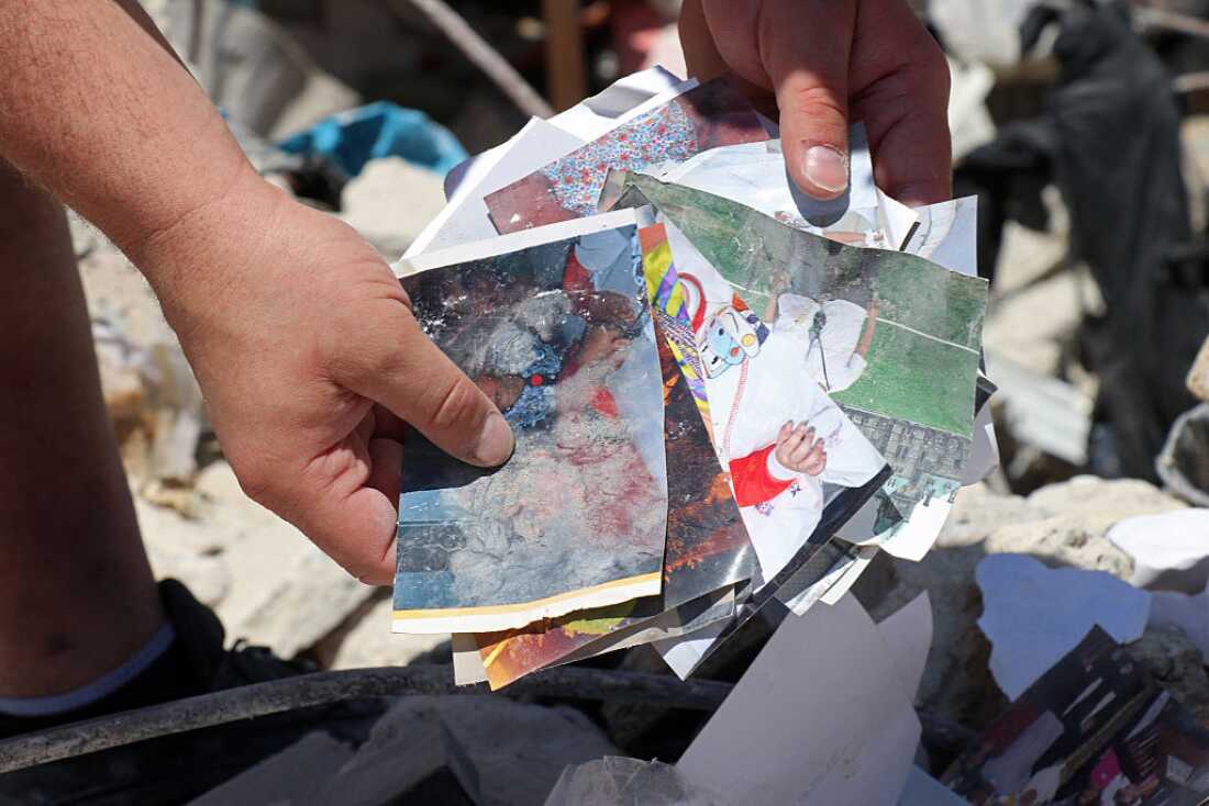 Resident Mohamad Ali Hijazi holds his damaged family photo album amid the rubble of destroyed buildings at a residential area in Tyre on April 23, 2026.