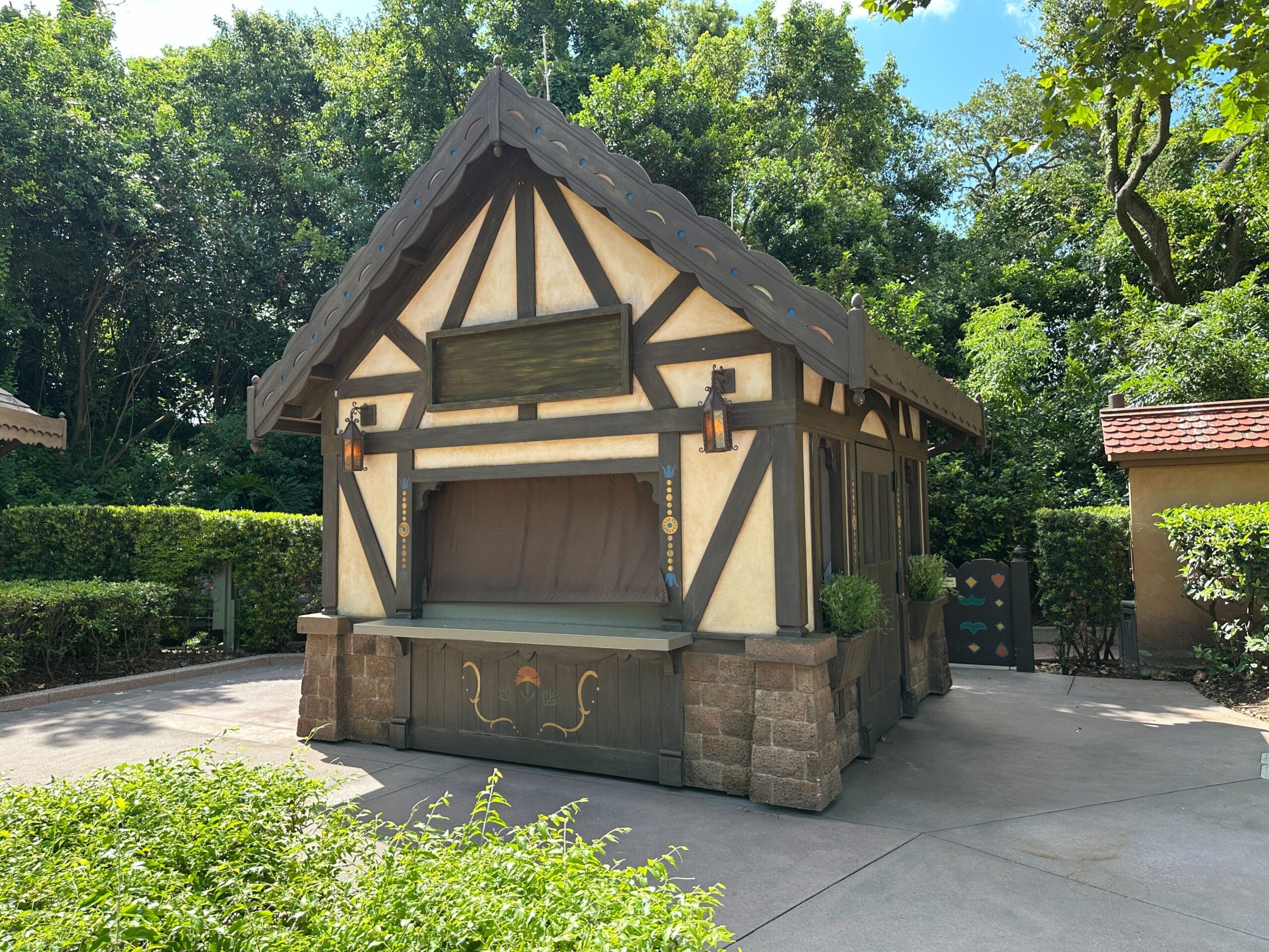 A small, fairytale-style wooden booth stands nestled in greenery at the 2025 EPCOT International Food & Wine Festival.