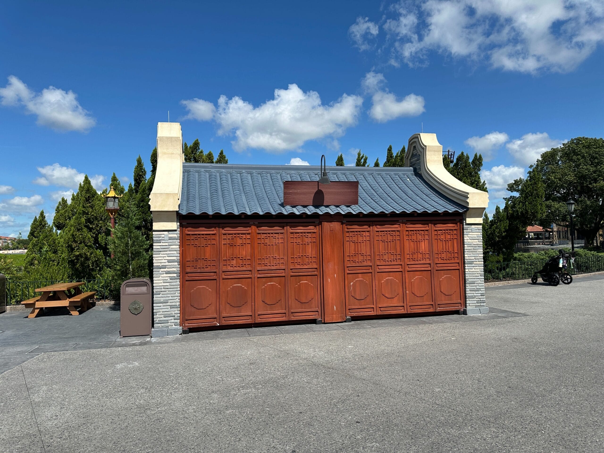 A closed pavilion with ornate wooden doors hints at preparation for the 2025 EPCOT International Food & Wine Festival.