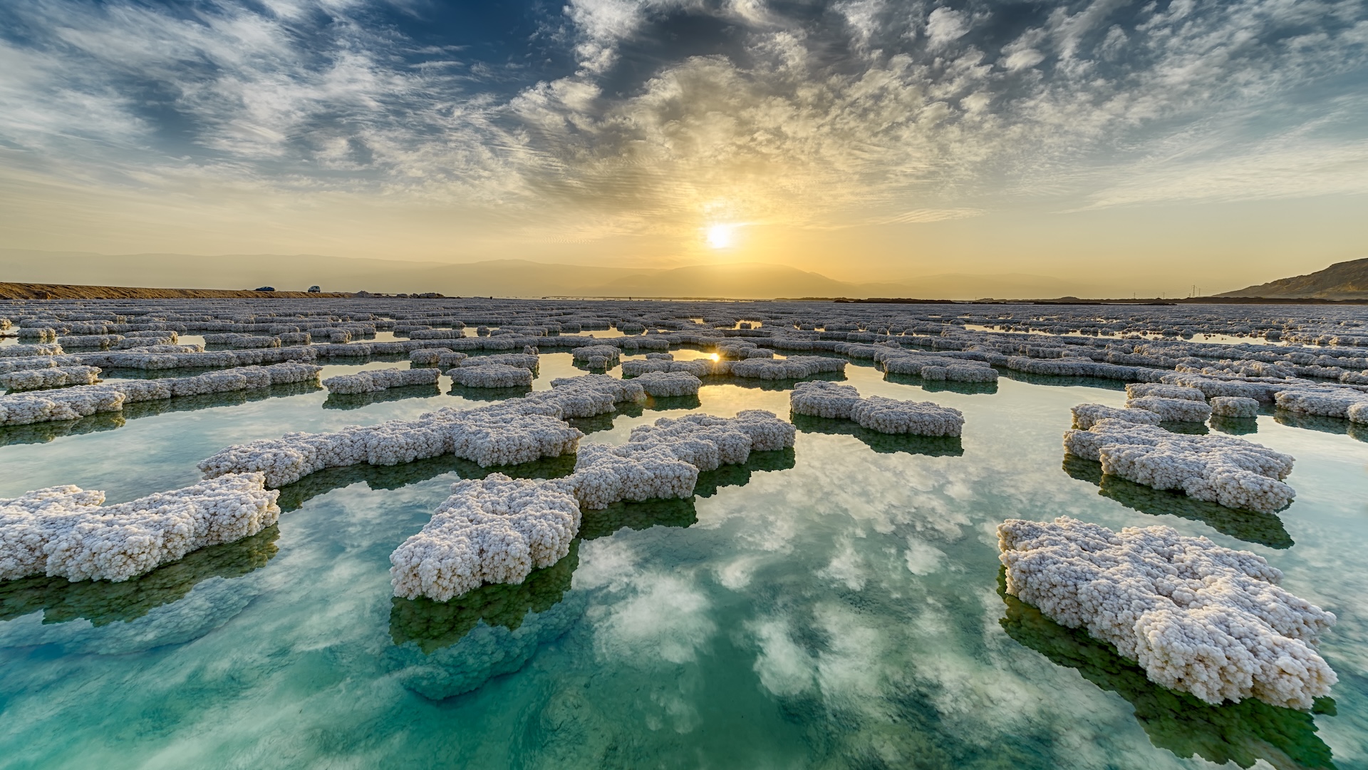 a photo of large ice crystals forming on the surface of the Dead Sea at sunset
